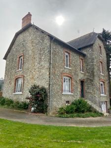 an old stone building on a field of grass at Les hortensias in Grand-Fougeray