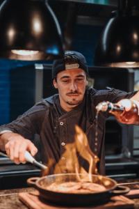 a man is preparing food in a frying pan at Revier Mountain Lodge Lenzerheide in Lenzerheide