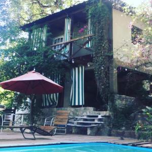 a house with an umbrella and a swimming pool at Namasté Casa Rural in Vaqueros