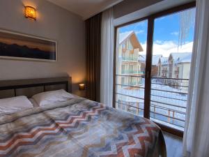 a bedroom with a bed and a large window at New Gudauri Alpen Apartments in Gudauri