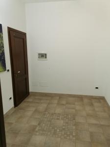 Camera bianca con porta e pavimento piastrellato. di Ciappella a Partanna