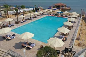 法耶德的住宿－Jewel Fayed Hotel，享有带椅子和遮阳伞的游泳池的上方景色