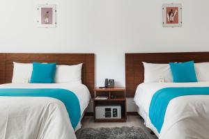 2 camas con sábanas azules y blancas en una habitación en REEC Latacunga by Oro Verde Hotels en Latacunga