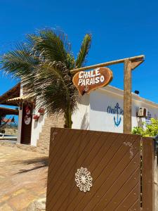 a sign in front of a building with a palm tree at POUSADA CHALÉ PARAÍSO - Icapui in Icapuí