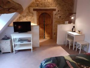 a living room with a tv and a table and a door at De Pierre et de Lumière in Jouhe