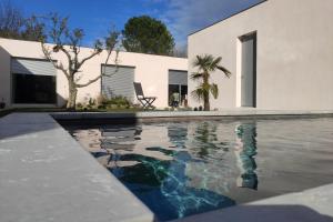 een zwembad voor een wit huis bij Carré de Lune in Villeneuve-lès-Avignon