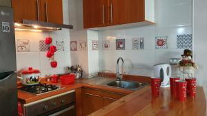 a kitchen with a sink and a counter with red cups at Hermoso Departamento Full Equipado in Pucón