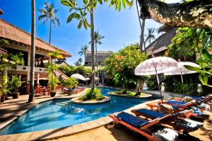 a pool at a resort with lounge chairs and umbrellas at Sativa Sanur Cottages in Sanur