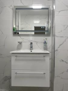 ein weißes Badezimmer mit einem Waschbecken und einem Spiegel in der Unterkunft Emily & Nasi in Plowdiw