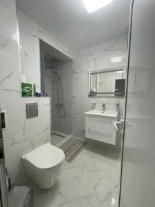 a white bathroom with a toilet and a sink at Emily & Nasi in Plovdiv