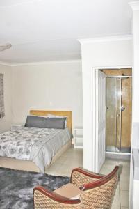 a bedroom with a bed and two chairs at Maruleng Guest House in Hoedspruit