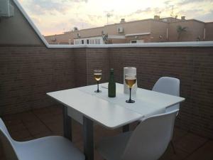 濱海羅克塔斯的住宿－Atico Amplio y Luminoso Roquetas de Mar Zona Centro Garaje Solo si esta Disponible，庭院里的一张带两杯葡萄酒的白色桌子