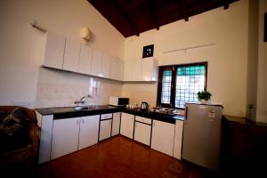 a kitchen with white cabinets and a refrigerator at Sky touch cottage & stays in Mukteswar +19 photos