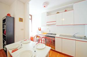 una cocina con armarios blancos y una mesa y sillas blancas. en DolceVita Apartments N 285, en Venecia