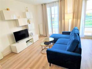 ein Wohnzimmer mit einem blauen Sofa und einem TV in der Unterkunft Sublime Appartemt 5 min Disneyland/Vallée Village/Val d'europe in Serris