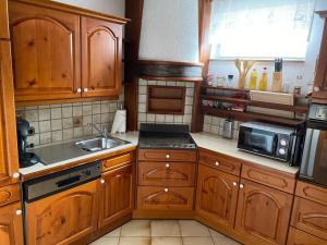 a kitchen with wooden cabinets and a sink and a microwave at Hotel - Pension Scheiblechner in Göstling an der Ybbs
