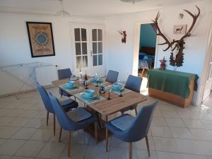 a dining room with a wooden table and blue chairs at Éva Apartmanház in Eger