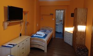 a small bedroom with a bed and a tv at Éva Apartmanház in Eger