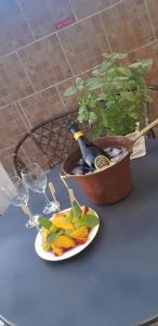 uma garrafa de champanhe e um prato de frutas e uma planta em vasos em B&B Cappotto civico 48 em Pompeia