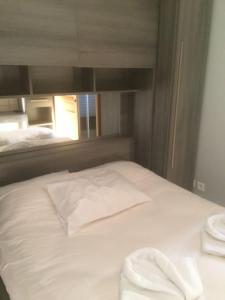uma cama branca num quarto com uma janela em Le Coin Tranquille au pied du Puy de Dôme em Pontgibaud