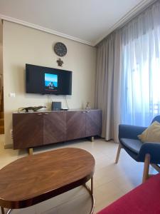 ein Wohnzimmer mit einem TV, einem Sofa und einem Tisch in der Unterkunft Grande apartamento, Sotavento 3, La Tejita, El Medano in Granadilla de Abona