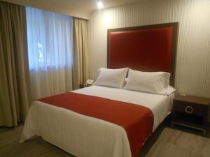 a bedroom with a large bed with a red headboard at Hotel Puente Real in Puebla
