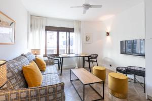 ein Wohnzimmer mit einem Sofa und einem Tisch in der Unterkunft Salado Triana Suites by Valcambre in Sevilla