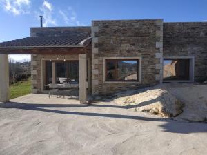 ein Steinhaus mit einer Terrasse und einem Tisch in der Unterkunft Casas Rurales en Peguerinos (P.N. del Guadarrama) in Peguerinos