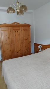 - une chambre avec un lit blanc et une armoire en bois dans l'établissement Appartamenti Bozzetta Marisa, à Cavalese