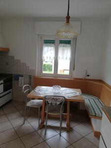 une cuisine avec une table et des chaises ainsi qu'une fenêtre dans l'établissement Appartamenti Bozzetta Marisa, à Cavalese
