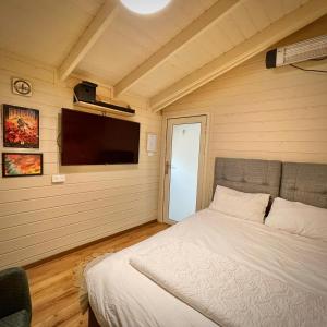 a bedroom with a bed and a flat screen tv at Vida Bhermon 2, one small wooden cabin in Majdal Shams