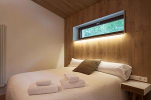 Schlafzimmer mit einem weißen Bett und einem Fenster in der Unterkunft Cabañas Deluxe Basajaun Basoa by IrriSarri Land in Igantzi