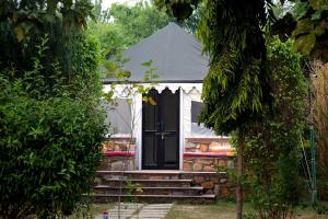 a house with a black door in a yard at Sultan Bagh Resort by The Sky Imperial in Sawāi Mādhopur