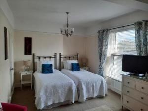 a bedroom with two beds with blue pillows at The Swallows B and B in Exmouth