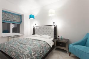 a bedroom with a bed and a blue chair at Sumskaya Apartment Lux in Kharkiv