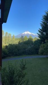 a mountain in the distance with a field and trees at Cabañas Kumelka in Villarrica