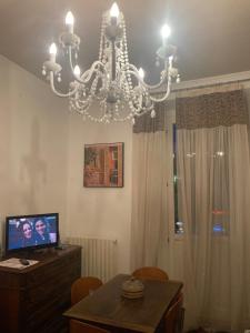 - un lustre dans le salon avec une table et une télévision dans l'établissement Casa vacanza sole lago…, à Intra