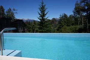 Una piscina azul con árboles al fondo. en Las Aguas Río Bonito, en Villa La Angostura