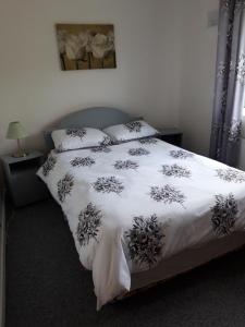 1 dormitorio con 1 cama con manta blanca y almohadas en Maggie's House, en Glenties