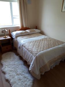 um quarto com uma cama com um edredão branco e uma janela em Maggie's House em Glenties