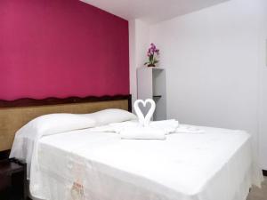 a bedroom with a white bed with a pink wall at Marlymar Apart Pousada in Natal