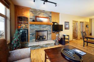 a living room with a stone fireplace and a table at Aspens 4406 in Big White