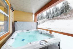 a jacuzzi tub sitting on a porch with a window at Aspens 4406 in Big White