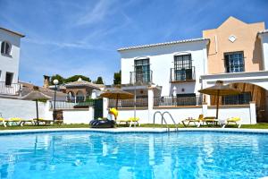 a swimming pool with chairs and umbrellas next to a building at Luna de Nerja in Nerja