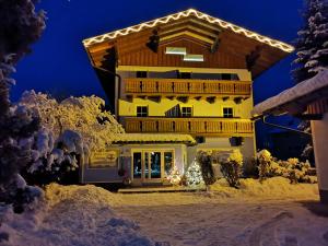 a house with a christmas lights on it in the snow at Aparthotel Landhaus Schwaighofer in Russbach am Pass Gschütt