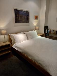 1 dormitorio con 1 cama grande con sábanas y almohadas blancas en cool room in shared house en York