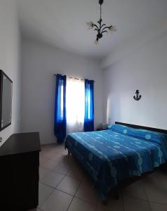 ein Schlafzimmer mit einem blauen Bett und einem TV in der Unterkunft Radici Blu intero alloggio in Siderno Marina