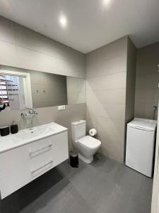 a white bathroom with a toilet and a sink at Apartamentos Cisneros in Alicante +33 photos