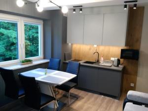 a kitchen with a white table and blue chairs at Kurort Kozubnik Apartament 33 Wellness &SPA in Porąbka