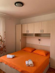 une chambre avec un lit orange avec deux serviettes dessus dans l'établissement Apartments Pahljina, à Rab
